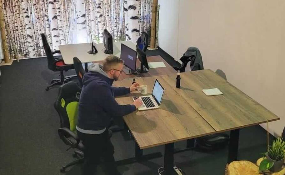 Pracoviště se spojenými stoly s dřevěnou deskou ve firmě Edurent v Regensburgu